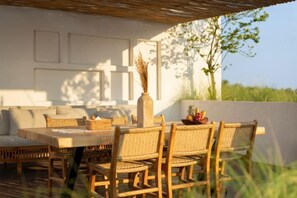 Ein Sitzbereich im Freien mit Tisch und Stühlen, einer Ziervase und Blick auf die Landschaft.