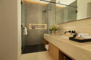 Une salle de bain moderne avec une douche à l’italienne en verre, un meuble-lavabo en bois et un grand miroir.