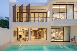A modern two-story house with a swimming pool, large glass doors, and a balcony. - Fenta Villa Canggu by Nakula (Bali)