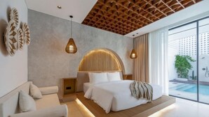 Une chambre moderne avec un grand lit, un canapé et une vue sur une piscine.