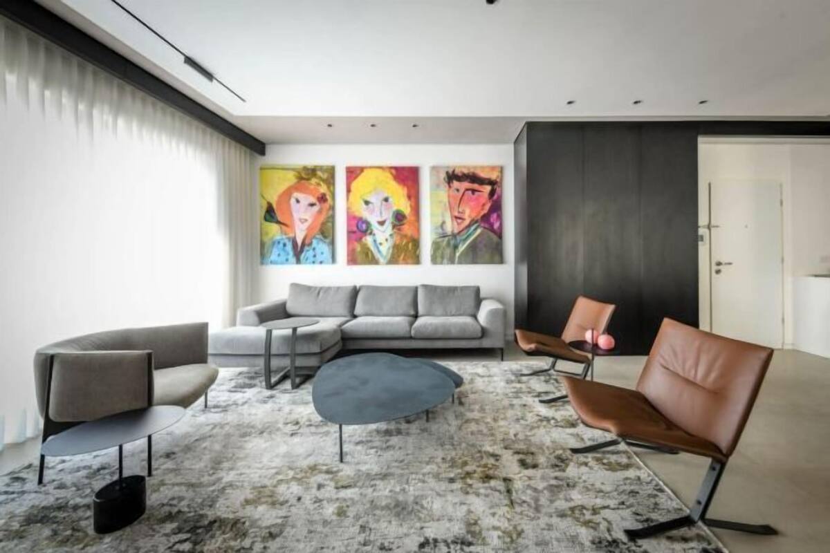 A modern living room with a sectional sofa, a round coffee table, and two leather chairs.