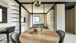 A modern dining area with a round table, black chairs, and a central light fixture. - Modern and Vibrant 1BR apt with Private Balcony (Tel Aviv)
