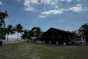 Una propiedad frente a la playa con un amplio edificio de madera, un garaje cubierto y vista al océano.