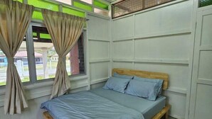 Un letto singolo con una testiera in legno, una finestra con tende e vista esterna.