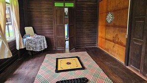 Una stanza con un bersaglio da freccette, un piccolo tavolo ricoperto da una tovaglia di merletto e una porta in legno con pannello verde.