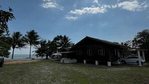 Una proprietà fronte spiaggia con una casa di legno, un'auto e una zona coperta con tetto bianco.