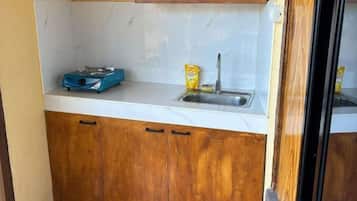 Una cocina compacta con encimera blanca, armarios de madera, una balanza azul y un recipiente amarillo.