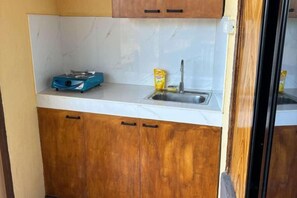 A compact kitchen with a white countertop, wooden cabinets, a blue scale, and a yellow container. - Kattegat Beachfront Villa (El Nido)