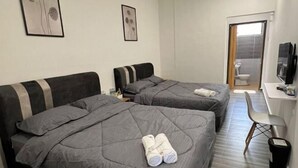 A hotel room with two beds, a desk, a chair, and a TV. - Kiwi Inn (Pengkalan Aor)