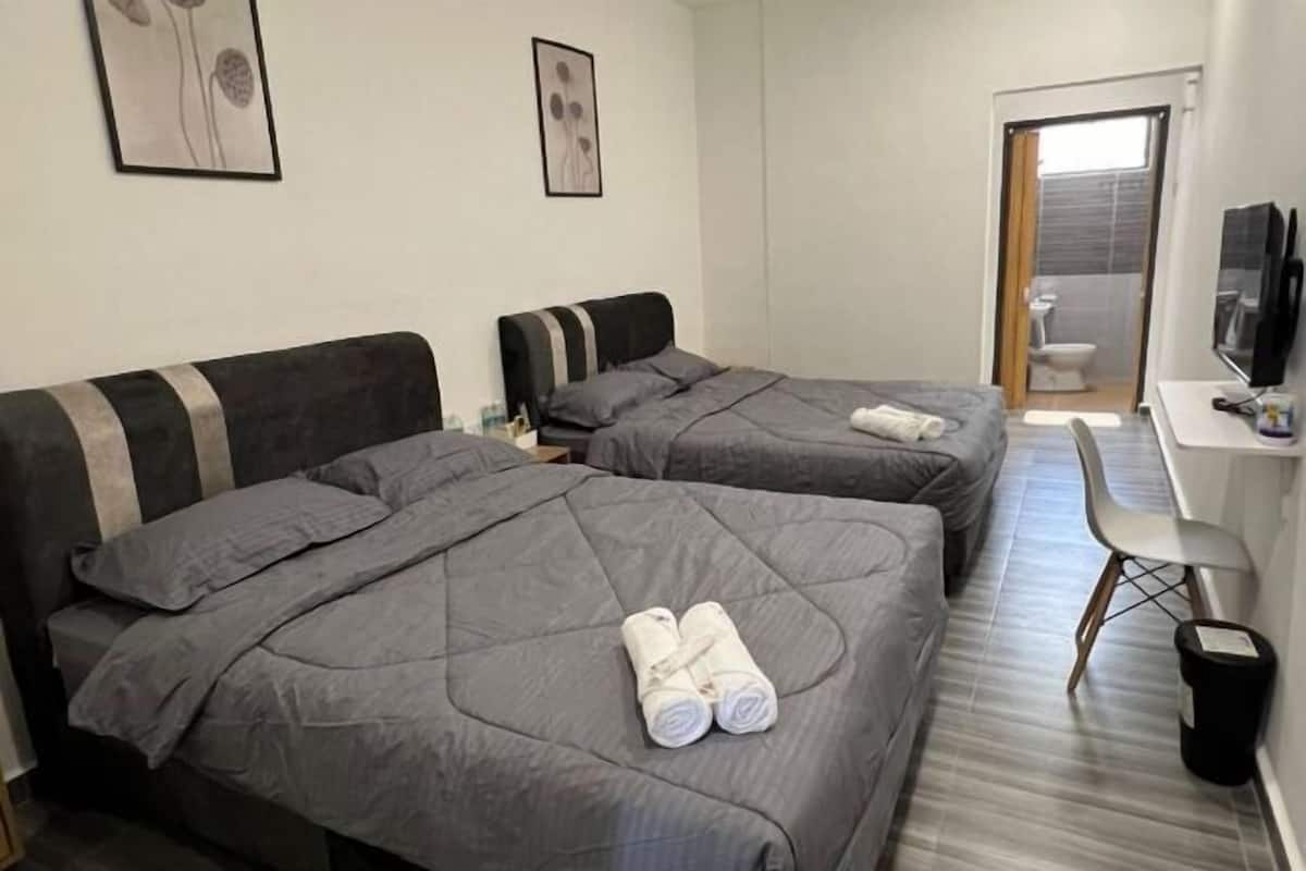 Hotellihuone, jossa on kaksi sänkyä, työpöytä, tuoli ja televisio.