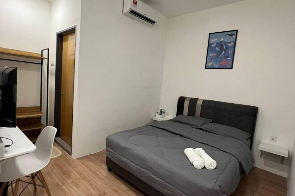 Moderni hotellihuone, jossa on sänky, työpöytä ja tuoli.