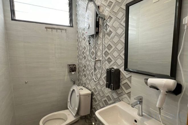 Un baño con inodoro, lavamanos y espejo.