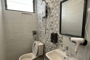 A bathroom with a toilet, sink, and a mirror.