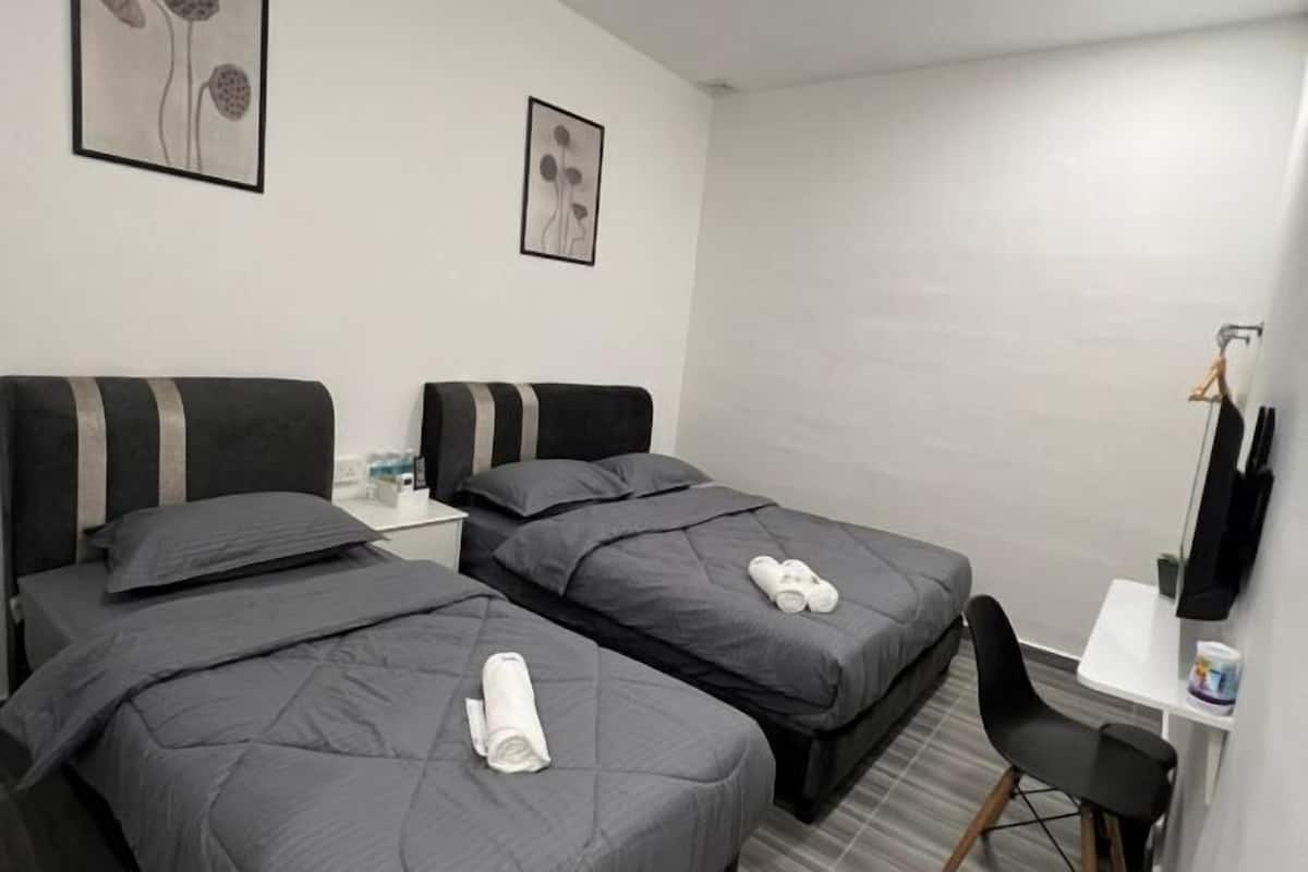 Hotellihuone, jossa on kaksi sänkyä, työpöytä, tuoli ja televisio.