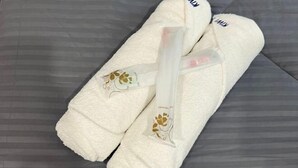 A pair of white towels with a floral design and the text "DENTAL ART" on a grey textured surface. - Kiwi Inn (Pengkalan Aor)