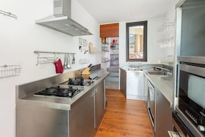A modern kitchen with stainless steel appliances, wooden flooring, and a view to the living area. - Jasmine Waterslide 5BR Pool Villa (Koh Samui)