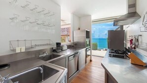 A modern kitchen with stainless steel appliances, a large window with a view of the ocean, and a wooden floor. - Jasmine Waterslide 5BR Pool Villa (Koh Samui)