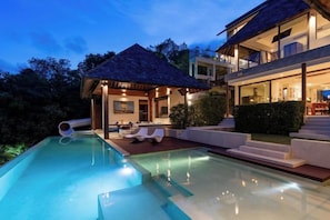 A swimming pool with lounge chairs, a covered seating area, and a staircase leading to a second-floor balcony. - Jasmine Waterslide 5BR Pool Villa (Koh Samui)