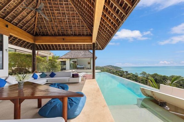 A poolside area with a wooden pergola, seating, and a view of the ocean. - Jasmine Waterslide 5BR Pool Villa (Koh Samui)
