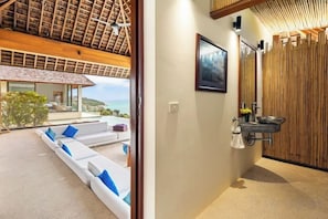 Een modern interieur met uitzicht op zee, een houten plafond en een zithoek met kussens.