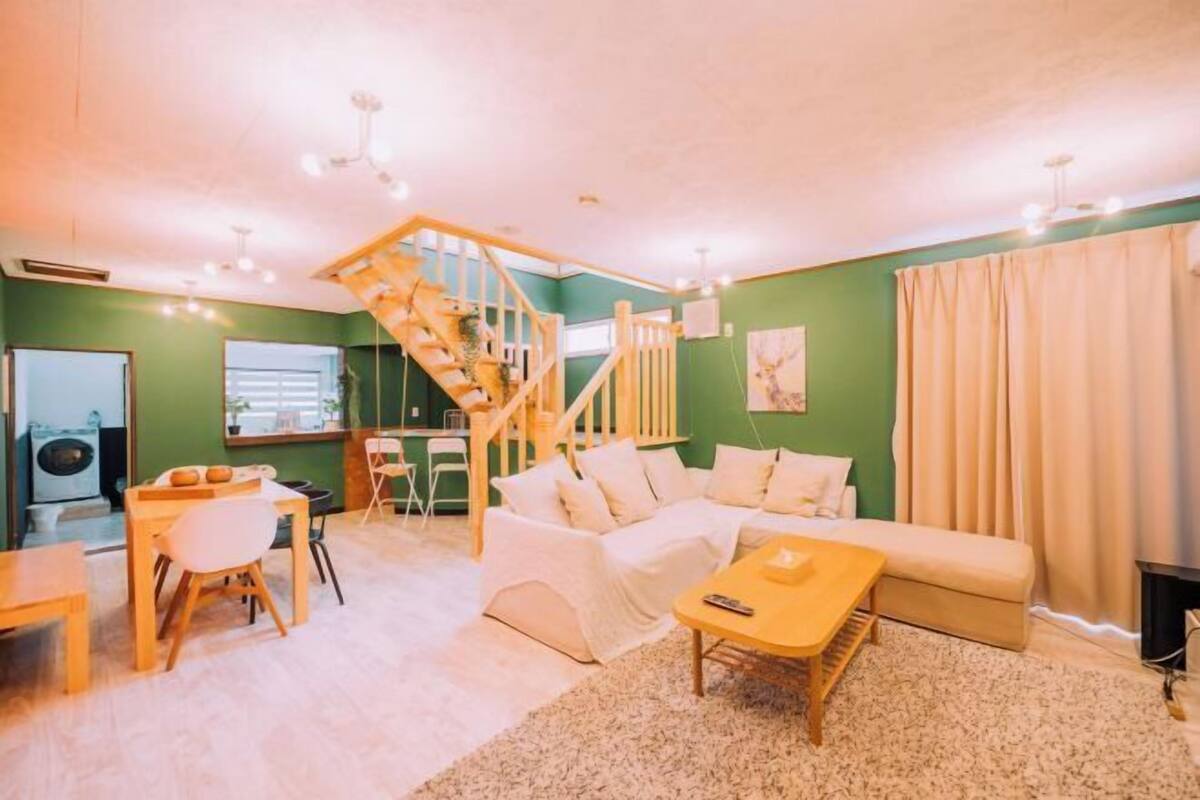 A cozy living room with a staircase, a sofa, a coffee table, and a dining area.