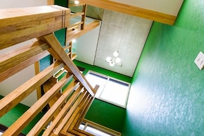 A multi-level wooden staircase with a view of a green wall and a ceiling light fixture. - Yuzawa Onsen Lodge House A (Minamiuonuma)