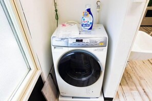 Una lavadora de carga frontal con una botella de detergente encima.