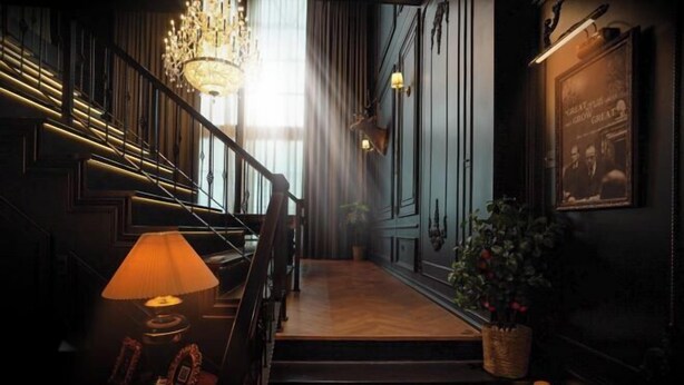 A staircase with a chandelier, a lamp, and a framed picture on the wall. - The Black Kingdom (Bangkok)