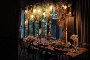 A dining table set with candles, flowers, and a chandelier. - The Black Kingdom (Bangkok)