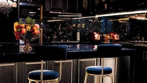 A modern kitchen with dark cabinetry, a marble backsplash, and a fruit bowl on the counter. - The Black Kingdom (Bangkok)