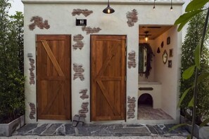 A building with two wooden doors, a stone wall, and a hanging light fixture. - The Black Kingdom (Bangkok)