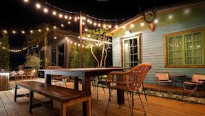 An outdoor patio with a wooden deck, a table, and wicker chairs. - The Black Kingdom (Bangkok)