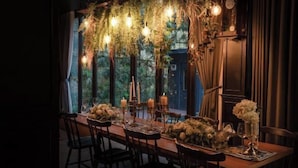 A dining table set with candles, flowers, and a rustic chandelier. - The Black Kingdom (Bangkok)