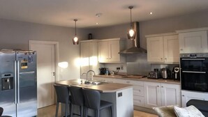 Een moderne keuken met een centraal eiland, roestvrijstalen apparatuur en hanglampen.
