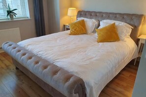 A bed with a tufted headboard, white bedding, and two yellow pillows.