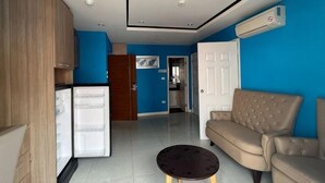 Una sala de estar con un sofá, una mesa de centro y un área de cocina con refrigerador.