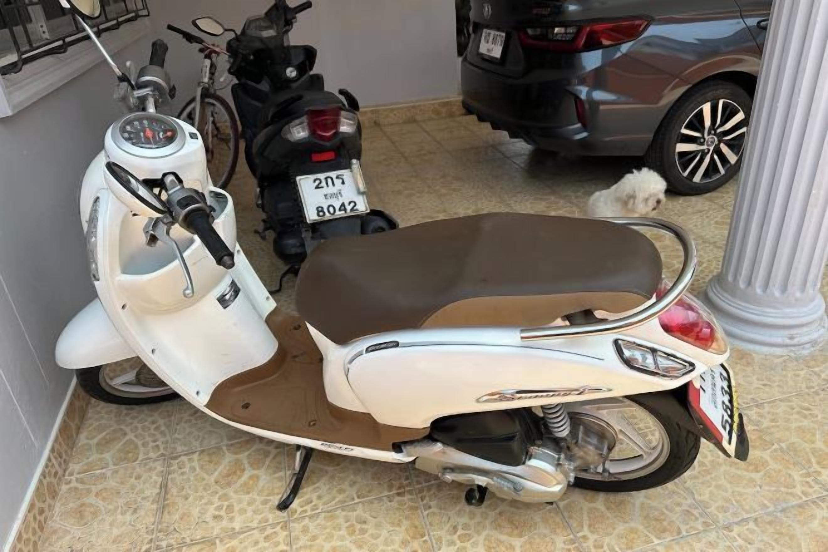 Una patineta blanca con asiento marrón estacionada en el interior.