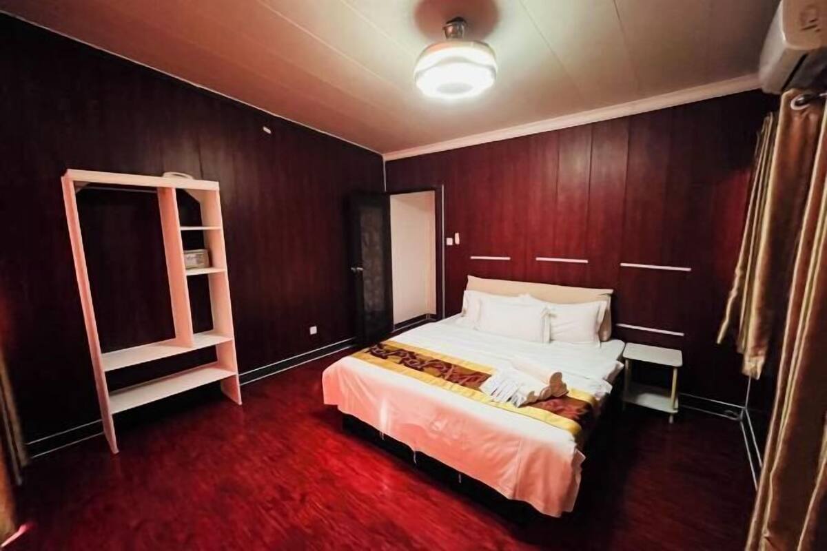 Un dormitorio con cama, armario, mesita de noche y lámpara en el techo.