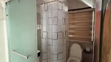 A compact bathroom with a shower curtain, toilet, and a door.