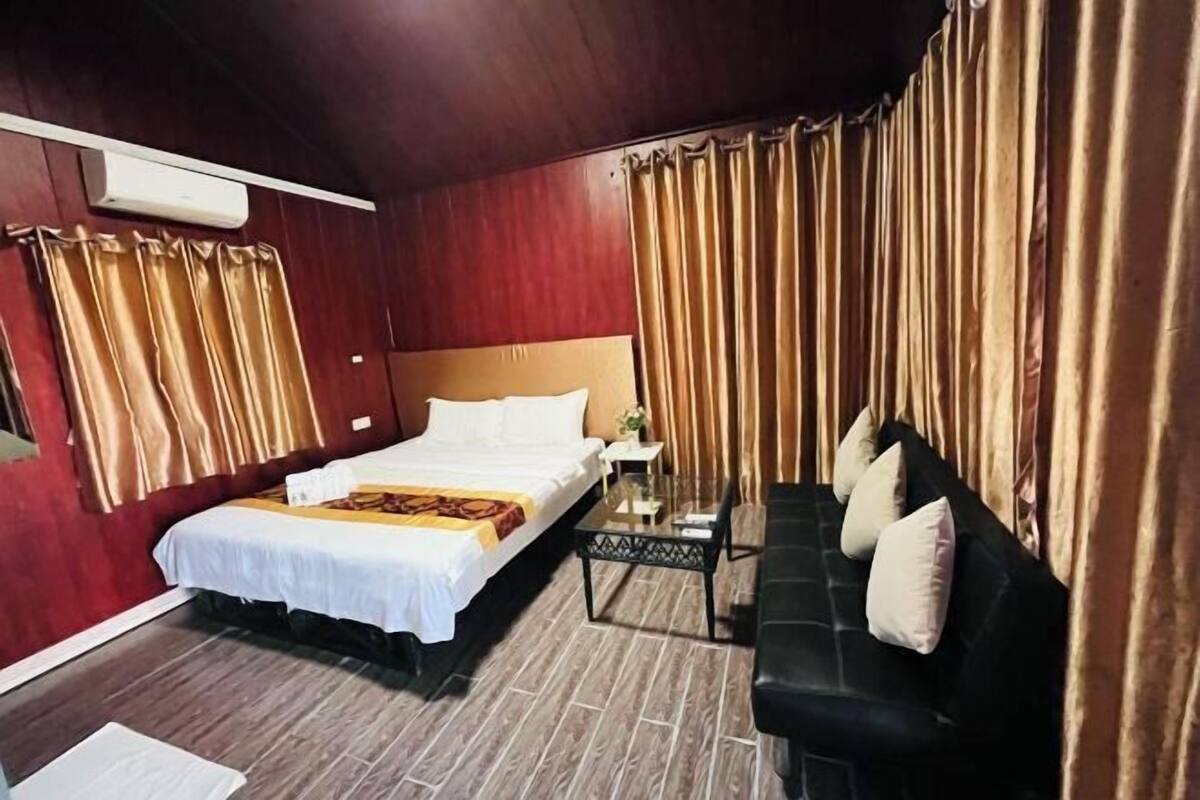 Una habitación de hotel con cama, sofá, una mesita y cortinas.