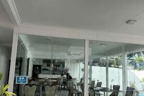 Un comedor moderno con divisiones de vidrio, diversas opciones de asientos y vistas al exterior.