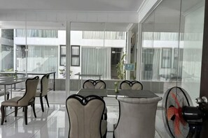 Un comedor moderno con una pared de vidrio, un ventilador y vistas al exterior.