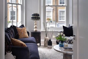 A modern living room with a sofa, a coffee table, and a lamp. - 317 Grand Maisonette (London)