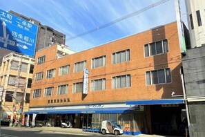 Un edificio a più piani con una tenda blu, un negozio ben visibile e un cielo sereno.
