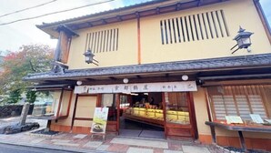 Un edificio japonés tradicional con techo de tejas, vigas de madera y un cartel.