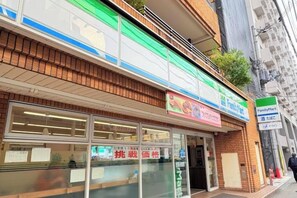 Une devanture de magasin avec une grande enseigne, un magasin de proximité FamilyMart et une entrée en verre.
