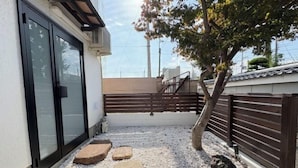 Un patio con cerdo de madera, un árbol y piedras para pisar.