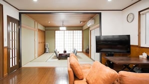 A traditional Japanese-style living room with tatami flooring, a sofa, a television, and a sliding door. - Relaxing stay Fukunosou - Convenient Access Hakata (Fukuoka)