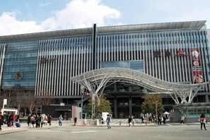 A modern building with a glass facade and a distinctive metal canopy structure in front. - Relaxing stay Fukunosou - Convenient Access Hakata (Fukuoka)