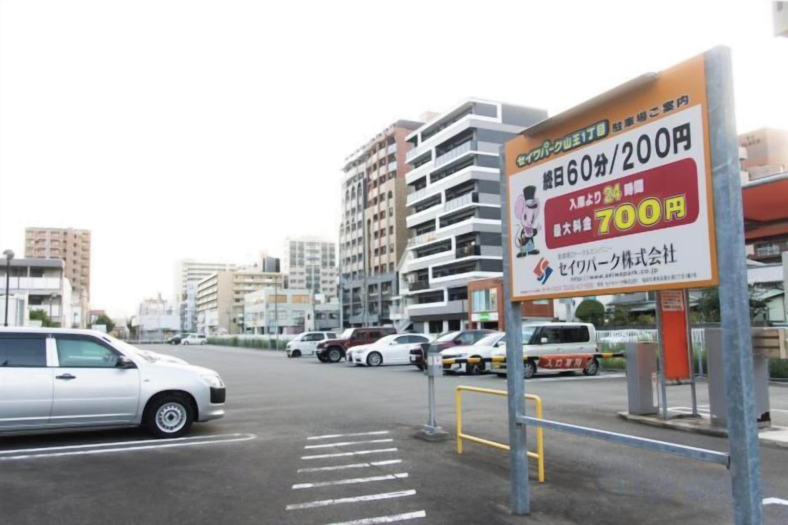 Un estacionamiento con un cartel que indica una tarifa de estacionamiento de 60 minutos por 200 yenes y una tarifa de 700 yenes por 2 horas.